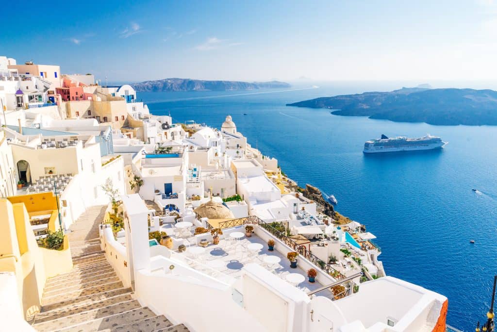 Scenic view of Santorini with white buildings and a cruise ship in the sea.